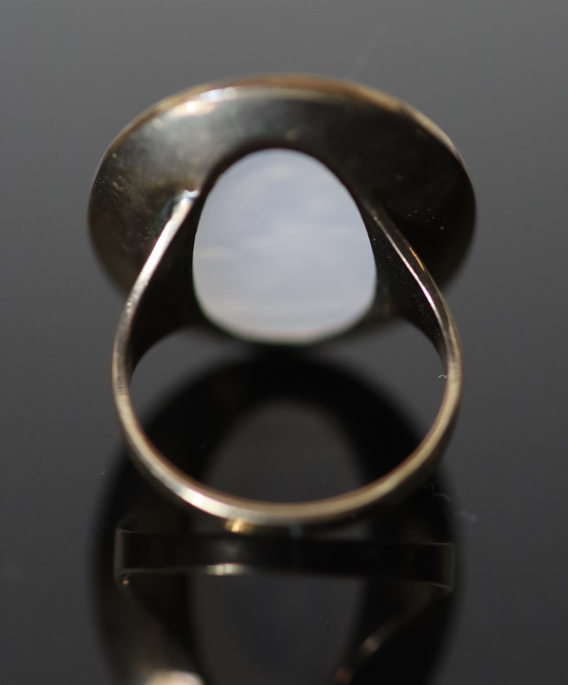 An early 19th century gold and white agate oval intaglio ring, carved with a seated figure,